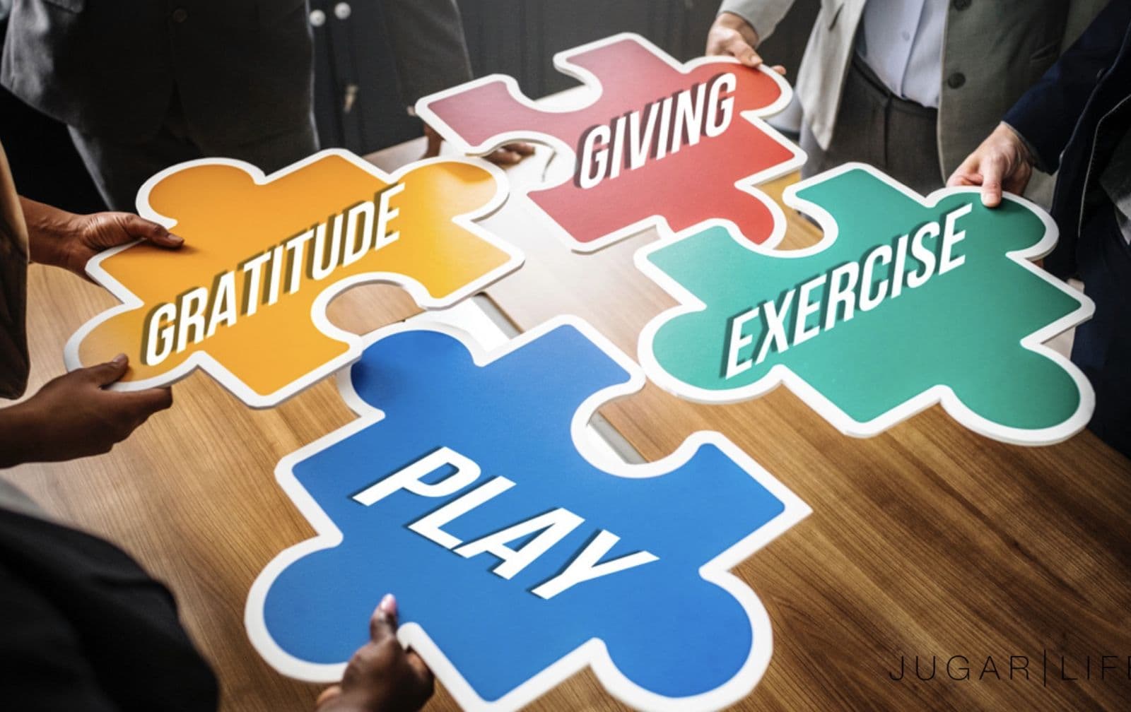 Four people fitting together giant puzzle pieces labelled Gratitude, Giving, Exercise and Play