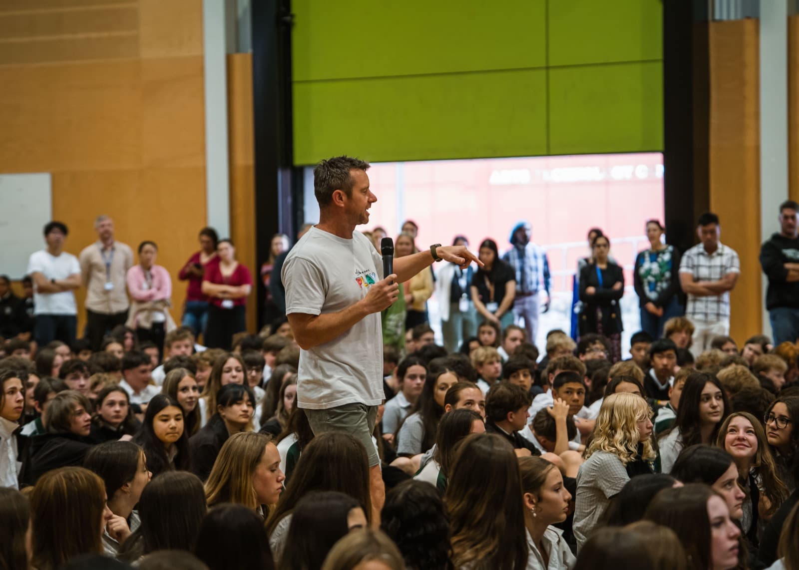 Dale Sidebottom leading a game in front of a packed hall of secondary students