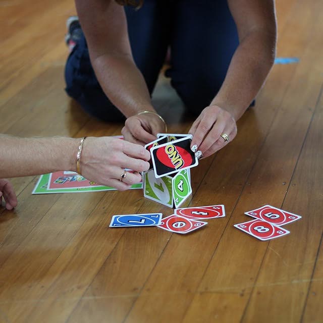 Two people playing a card game together on a hall floor during a session